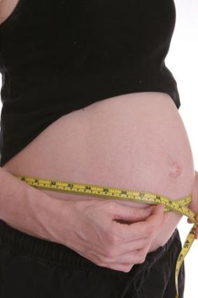 Pregnant woman measuring her belly at week 28
