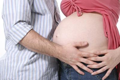 New dad holding pregnant mom's belly