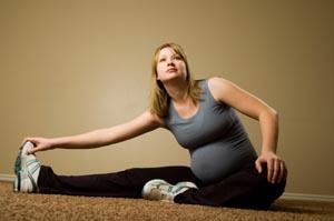 Seemingly pregnant woman stretching on floor