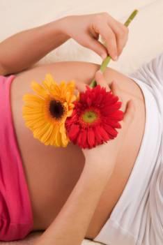 Pregnant woman holding flowers over her belly