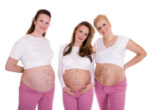 Three pregnant women showing their bellies
