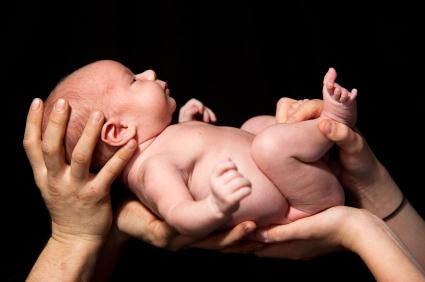 Hands holding up a newborn baby