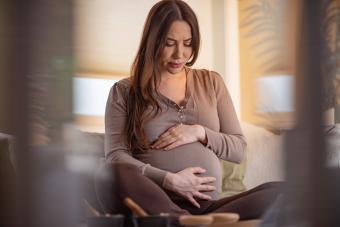 Pregnant woman feeling pain while sitting in living room