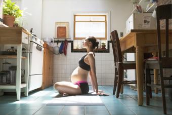 Pregnant woman doing yoga in kitchen at home