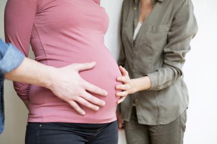 Two hands touching a belly of a pregnant woman