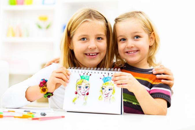 Two girls holding princess drawings