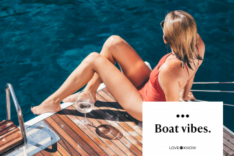 Woman at red bikini drinking wine while sunbathing at the yacht