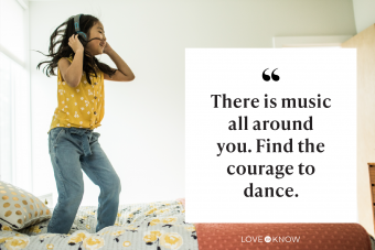 Young girl using headphones and dancing on her bed