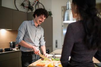 Hombre cocinando mientras su esposa mira