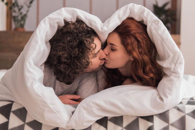 Pareja besándose bajo una manta