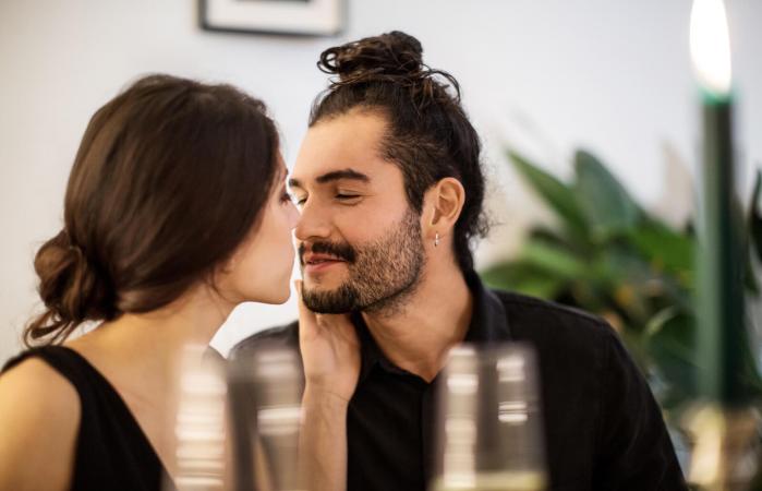 Pareja besándose durante la cena