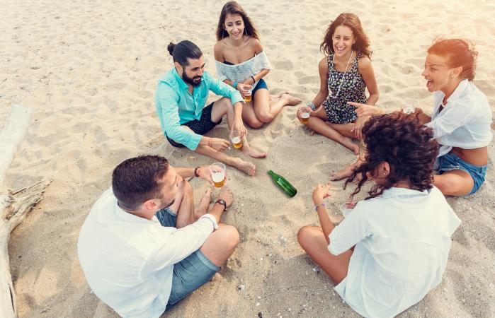 Grupo de amigos jugando a girar la botella en la playa