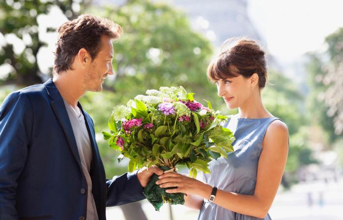 Hombre dando un ramo de flores a una mujer
