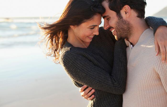 Pareja sonriente abrazándose en la playa