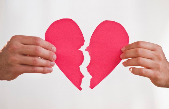 Dos manos sosteniendo un corazón de papel roto