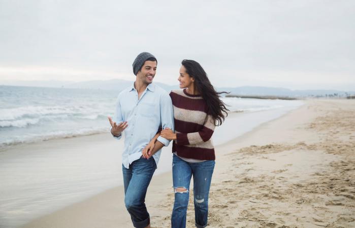 Pareja caminando y hablando en la playa
