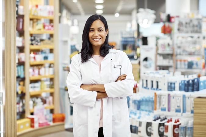 Pharmacist standing with arms crossed at pharmacy