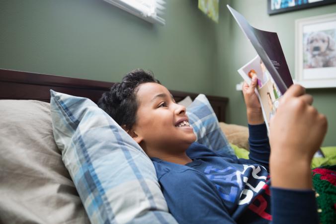 Boy reading magazine in bed