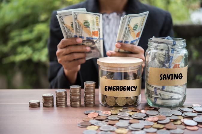 Man Counting Money With Jars And Coins On Table