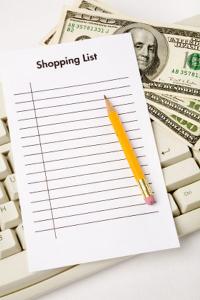 Shopping list and money on computer keyboard