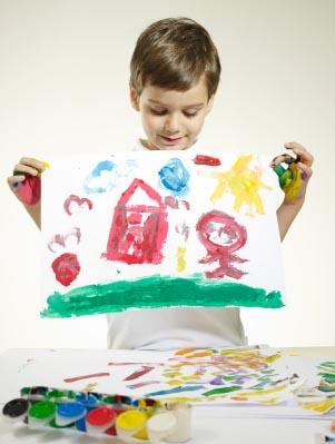 Little boy holding up artwork.