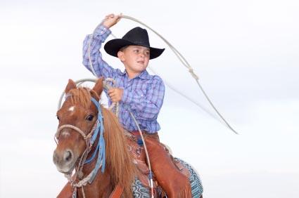 Young cowboy with lasso on horse.