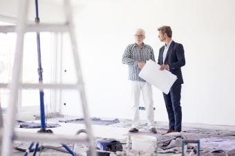 Man in suit and senior man talking on room under construction