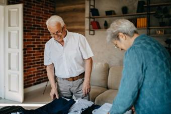 Senior couple laughing while packing suitcases