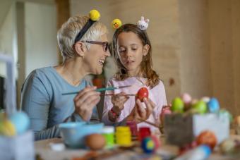 Senior woman and child decorating Easter eggs