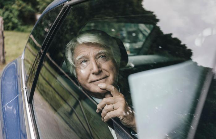 Senior man looking through car window