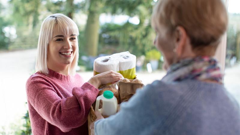 Neighbor Helping Senior Woman With Shopping