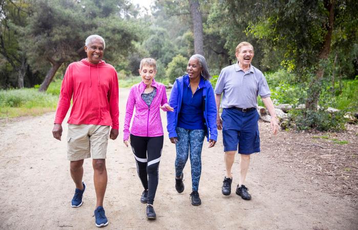 senior friends walking along a forest trail