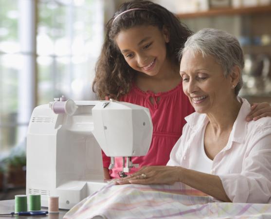 Grandmother teaching granddaughter how to sew