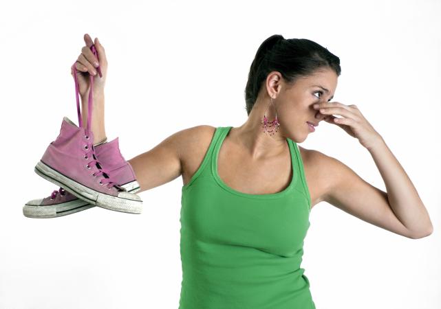 woman holding stinky shoes