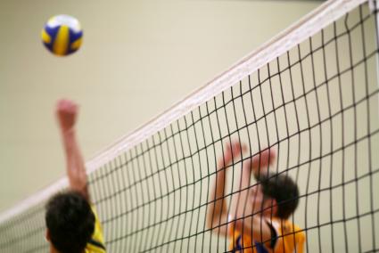 Young men in uniforms playing volleyball
