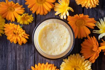 Jar of homemade body butter surrounded by flowers