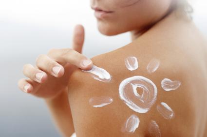 young woman with sunscreen lotion in shape of sun
