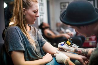 Artist making tattoo on woman's hand 