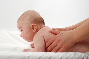 Baby having lotion rubbed on his back