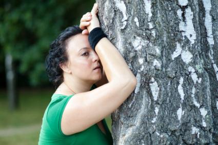 Exhausted woman leaning on tree; © Berc | Dreamstime.com