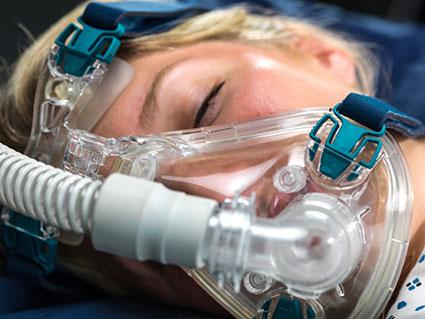 Woman sleeping and wearing a CPAP.