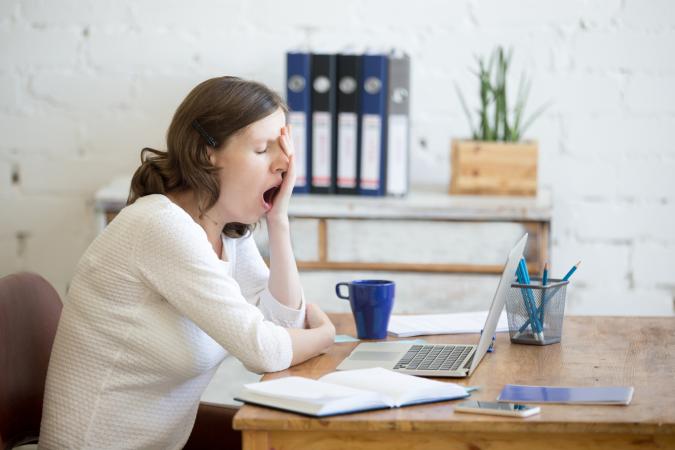 Sleepy woman yawning at desk