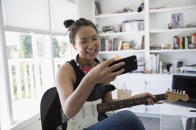 girl on cell holding electric guitar
