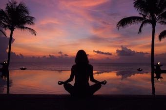 silhouette of woman meditating near pool