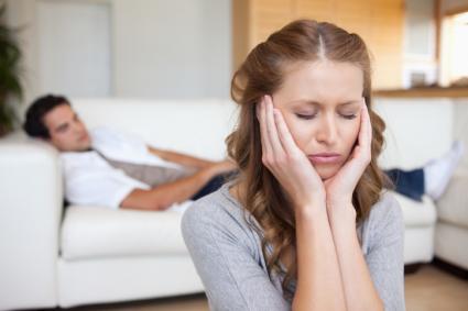 Woman with a headache man on sofa behind her