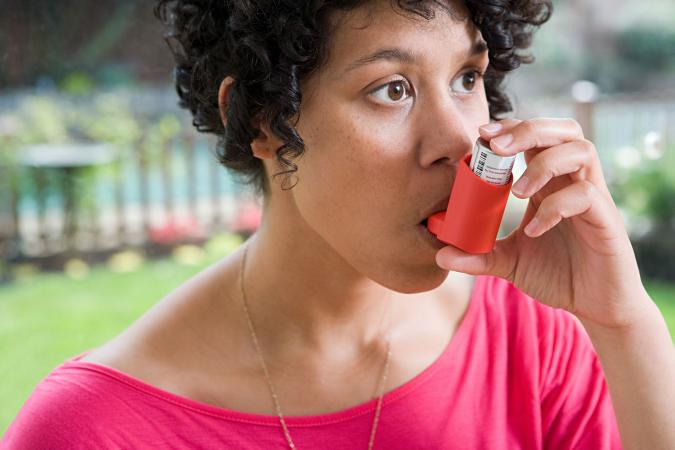 Woman using inhaler to treat asthma