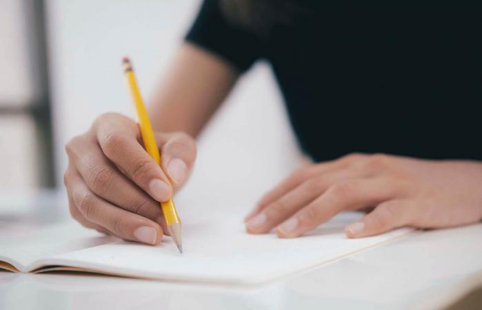 hands with pen writing on notebook