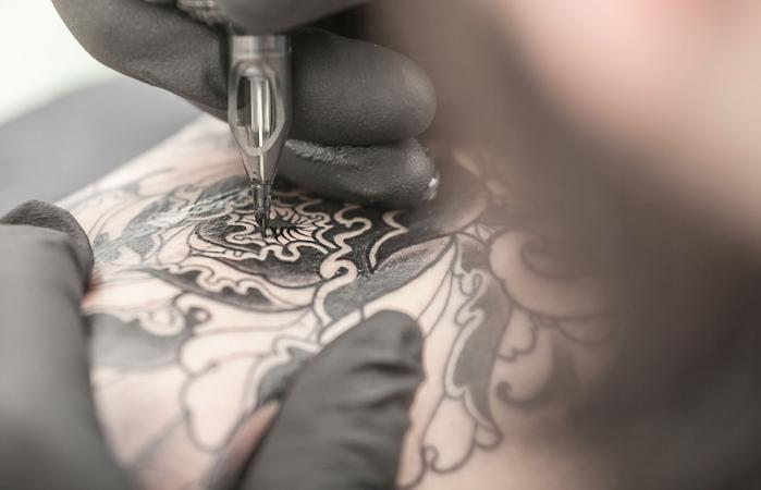 Tatuador dibujando en el brazo del cliente