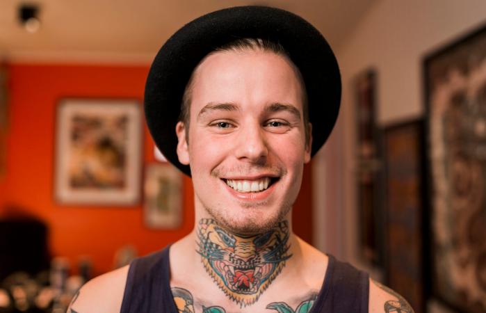 Chico sonriente con tatuaje en el cuello