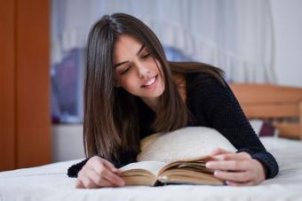 Teenage girl reading book on bed